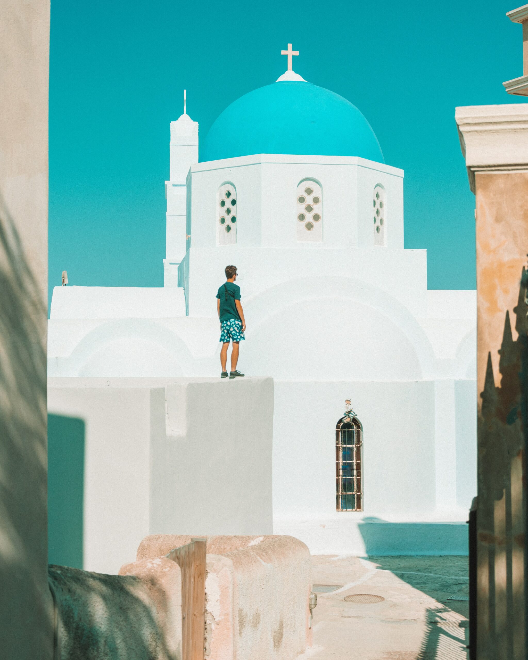 man standing in front of the blue domes in Santorini